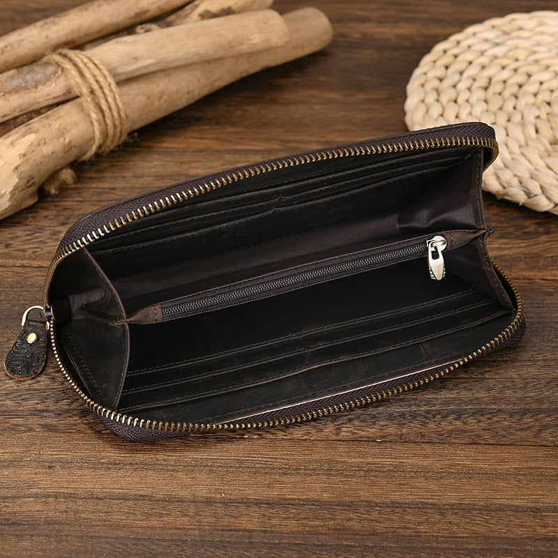 Open black leather wallet with gold zipper on a wooden surface