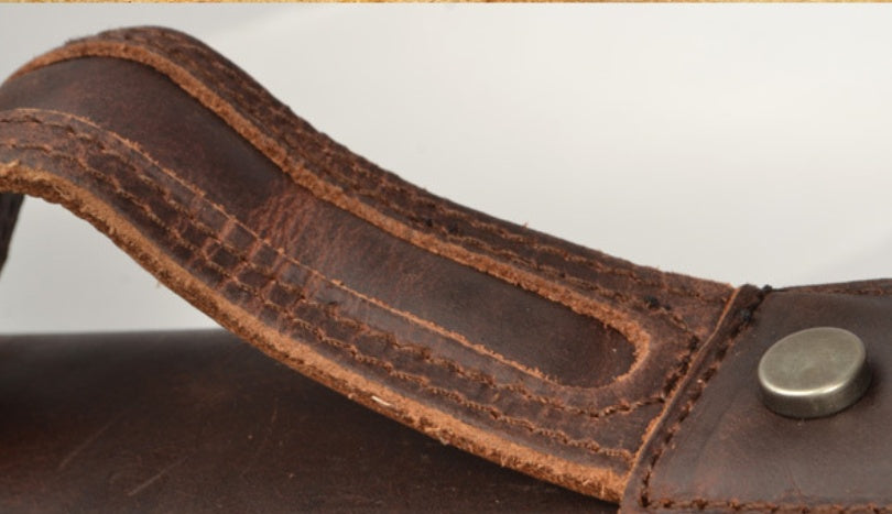 Close-up of a brown leather strap with stitching detail on a light gray background