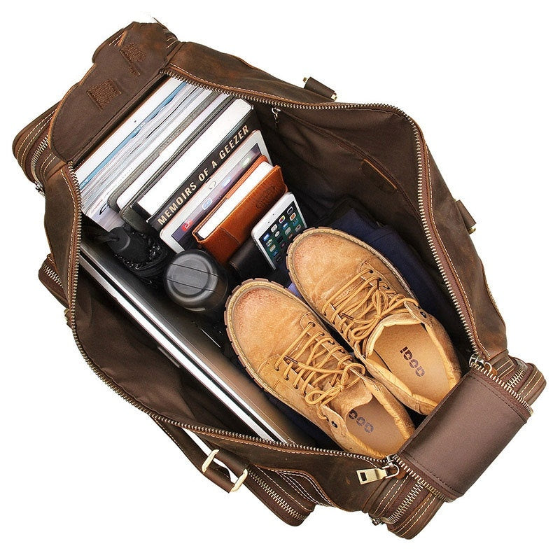 Brown leather duffel bag with shoes and other items on a white background