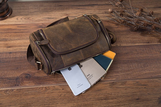 Brown leather bag with phone and books on a wooden surface