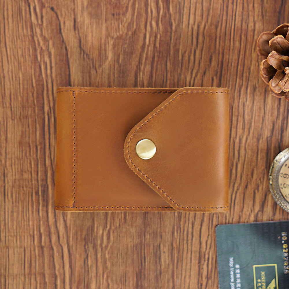 Brown leather wallet with a gold button on a wooden surface