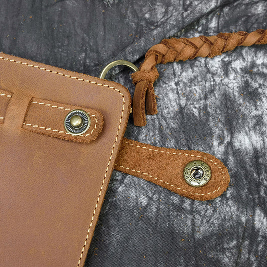 Close-up of a brown leather strap with metal clasps on a textured gray background