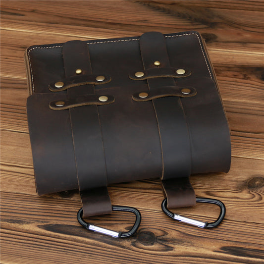 Brown leather straps with metal carabiners on a wooden surface