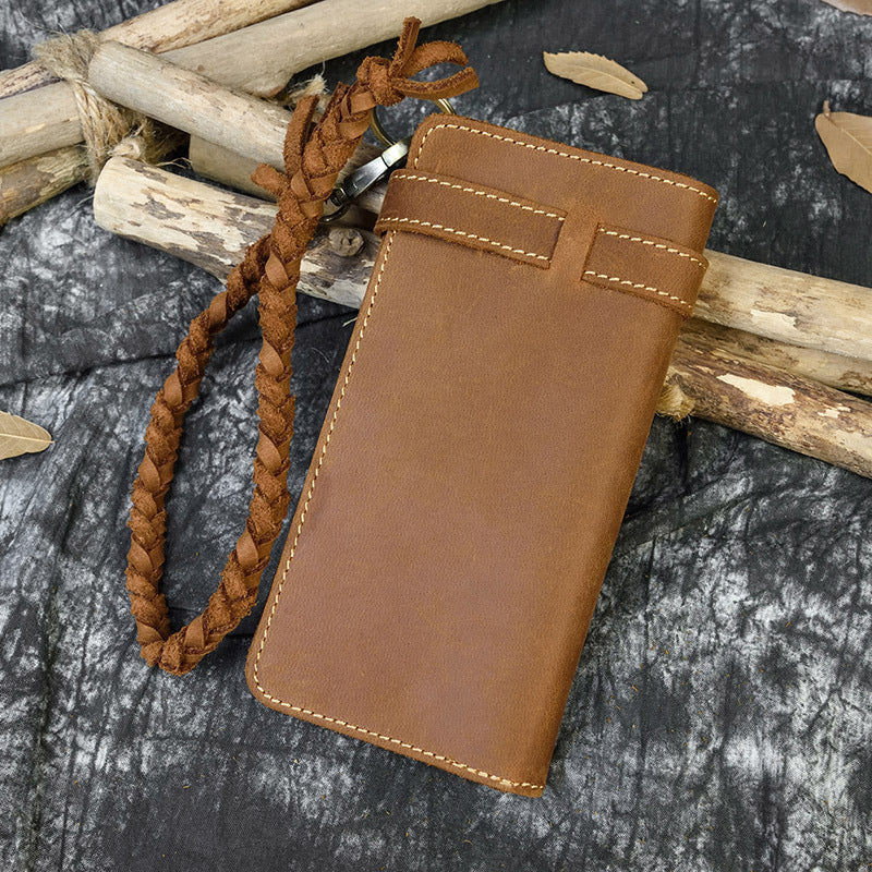Brown leather phone case with braided strap on a textured surface