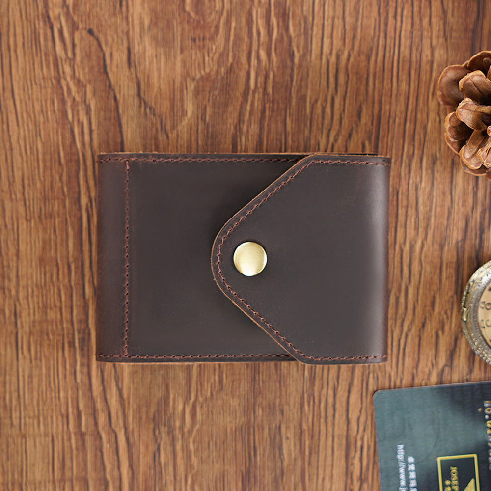 Brown leather wallet with a gold button on a wooden surface