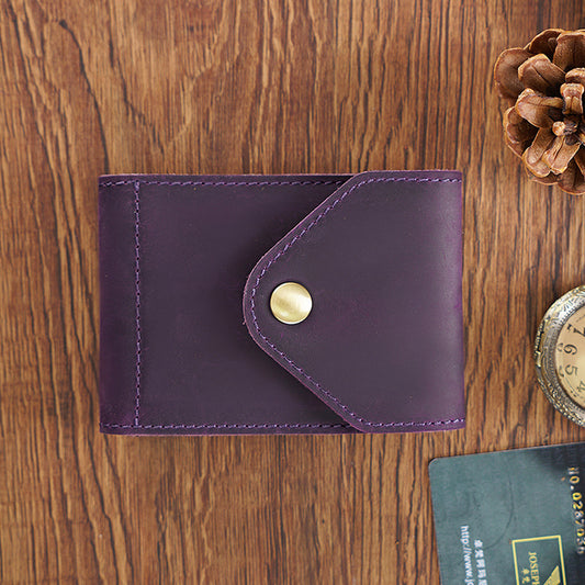 Purple leather wallet with a gold button on a wooden surface