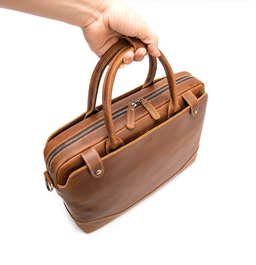 Brown leather briefcase held by a hand on a white background