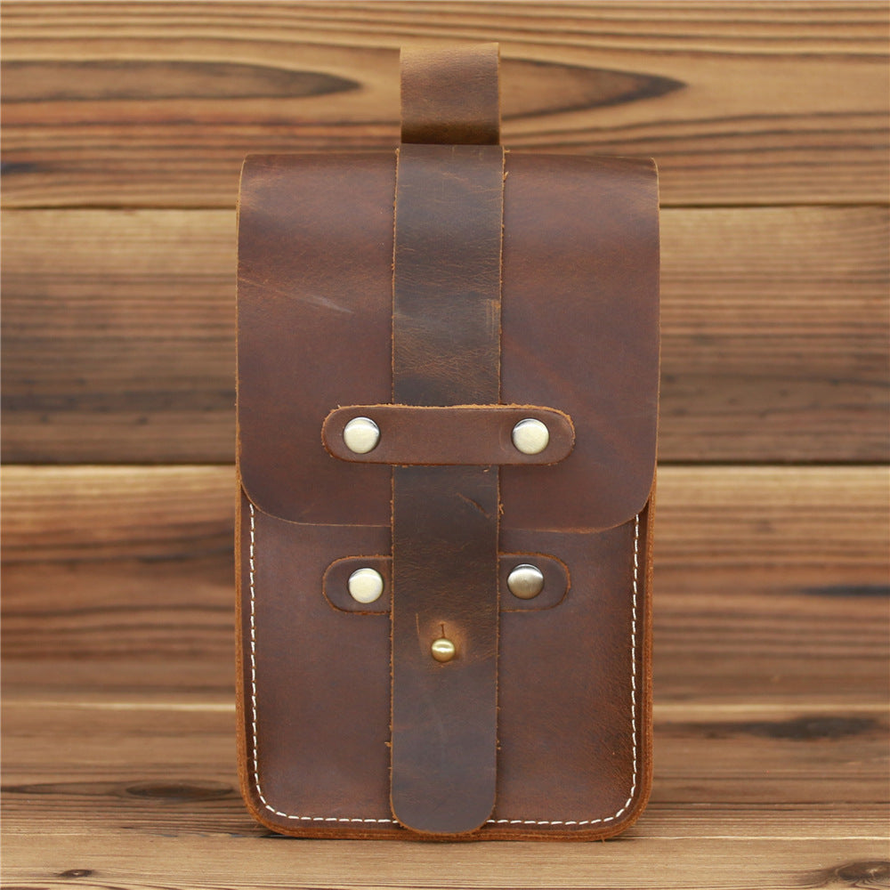 Brown leather pouch with metal clasps on a wooden background