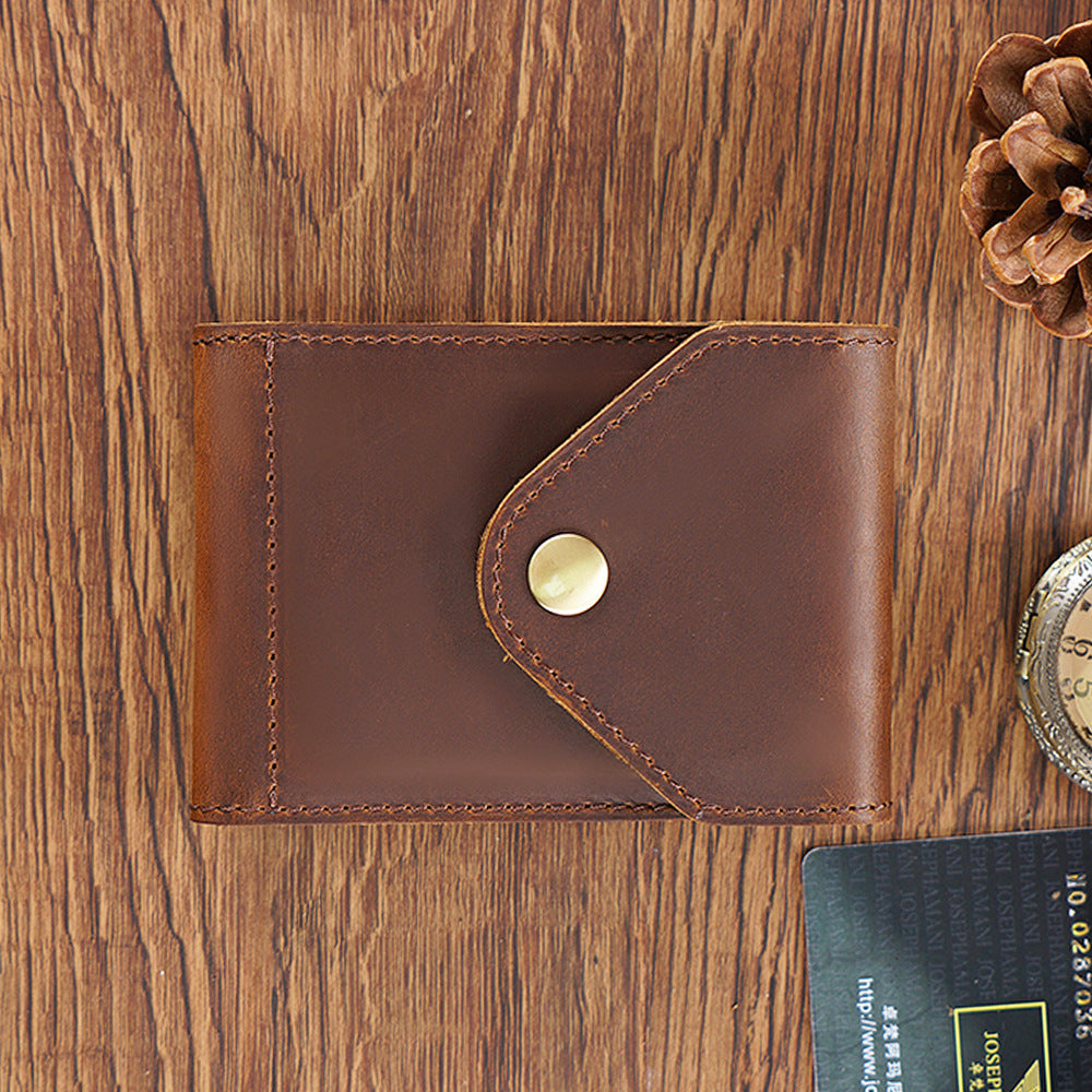 Brown leather wallet with a gold button on a wooden surface