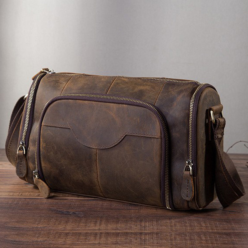 Brown leather duffel bag on a wooden surface with a gray background