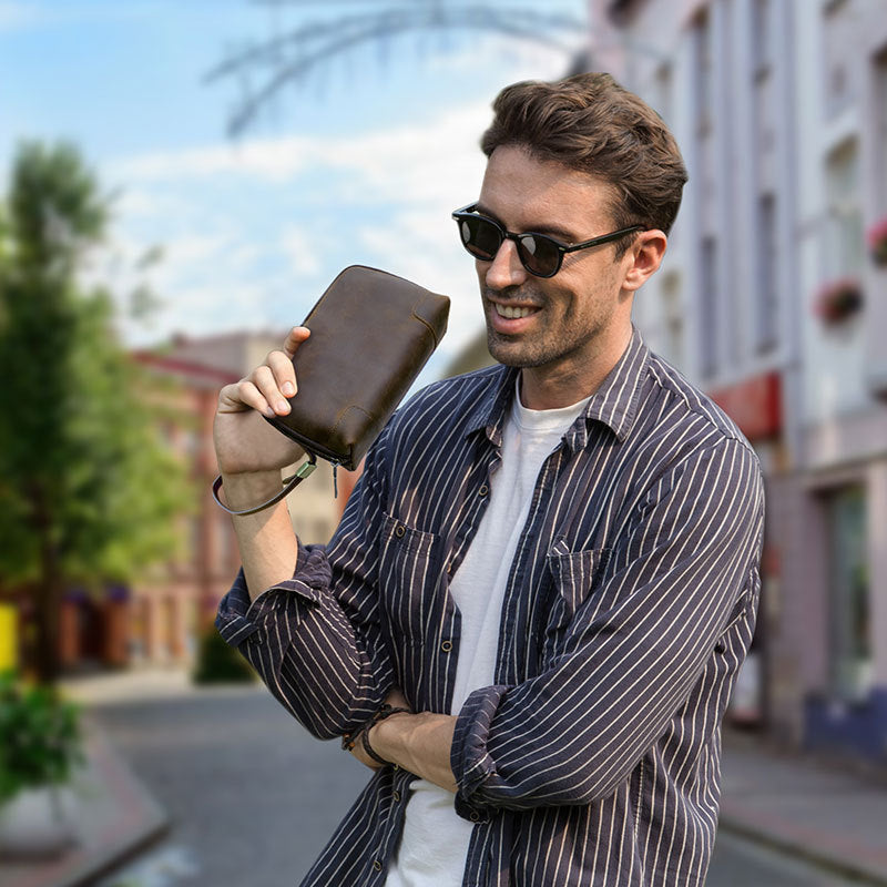 Man holding a brown leather wallet on a city street