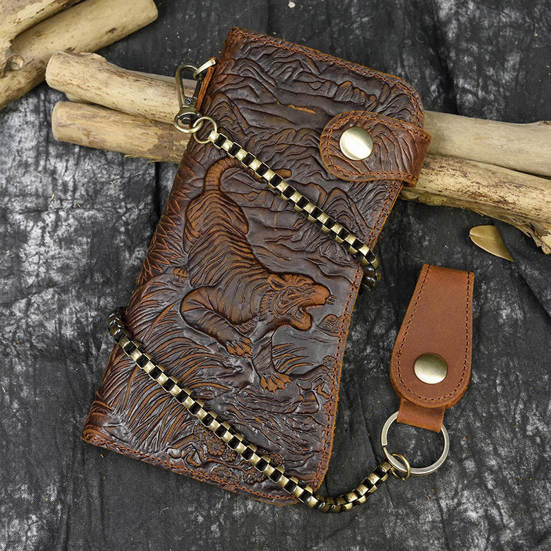 Brown leather wallet with tiger design and keychain on a dark surface