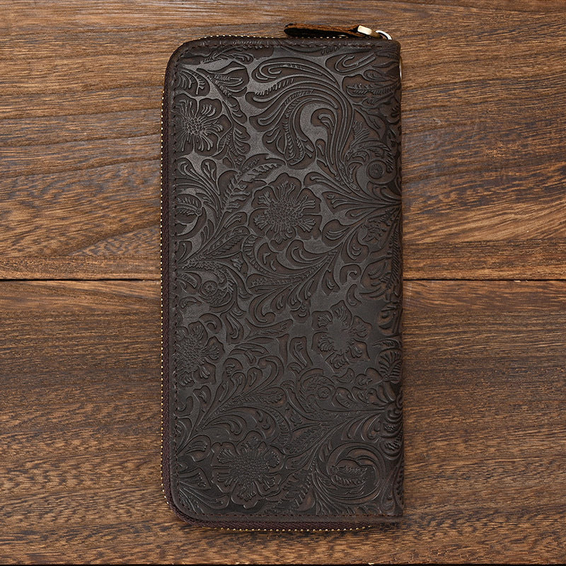 Dark brown leather wallet with floral patterns on a wooden surface