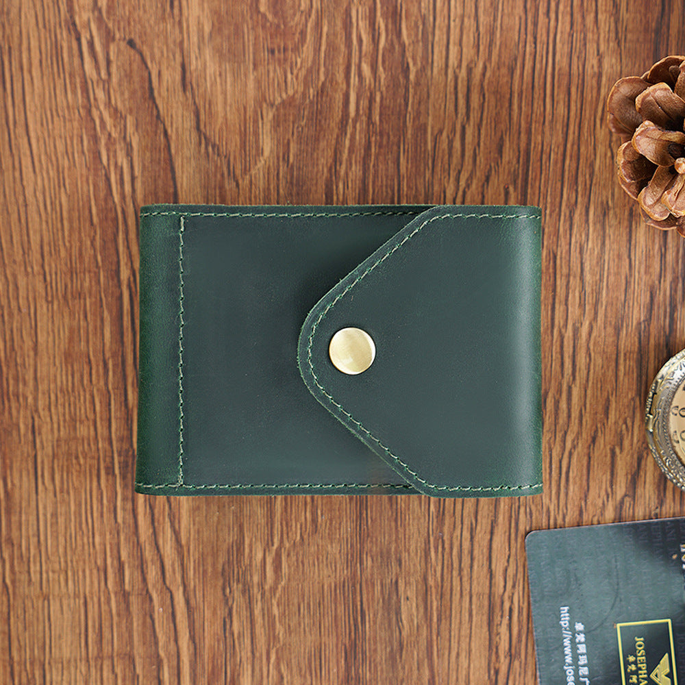 Green leather wallet with a gold button on a wooden surface