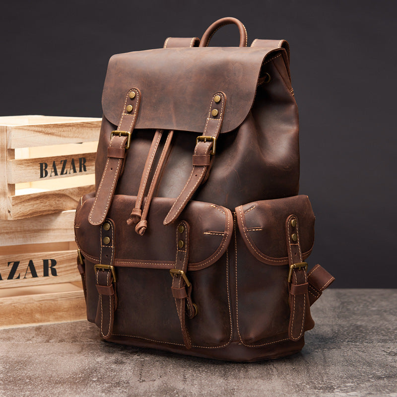 Brown leather backpack on a dark background with wooden crates.