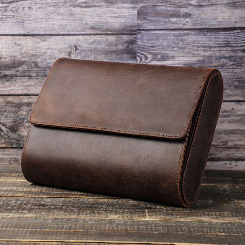 Brown leather clutch bag on a wooden surface with a rustic background
