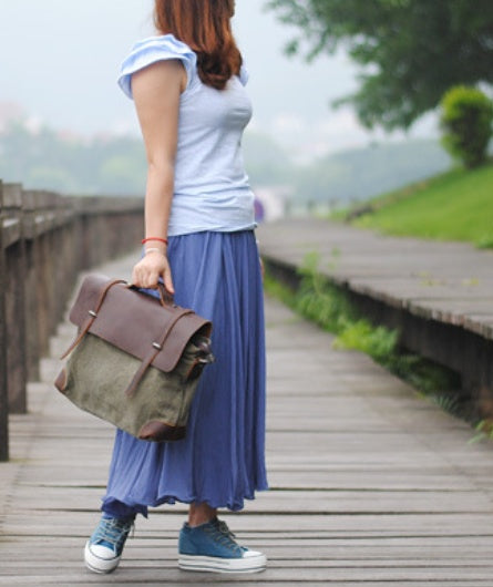 Person holding a brown and green bag on a wooden pathway with a blurred natural background