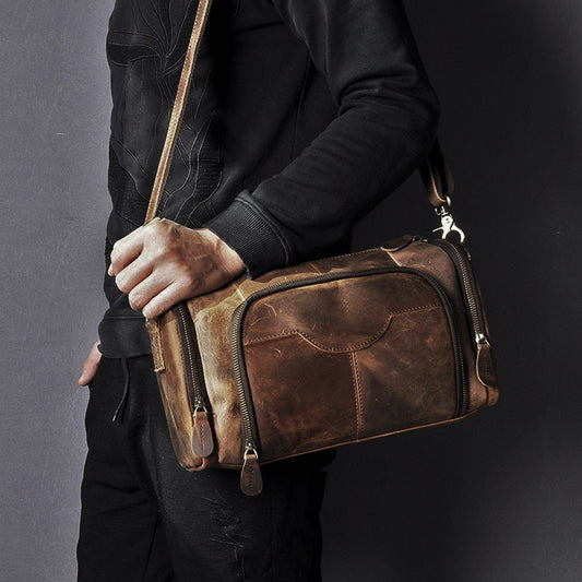Person holding a brown leather bag against a dark background