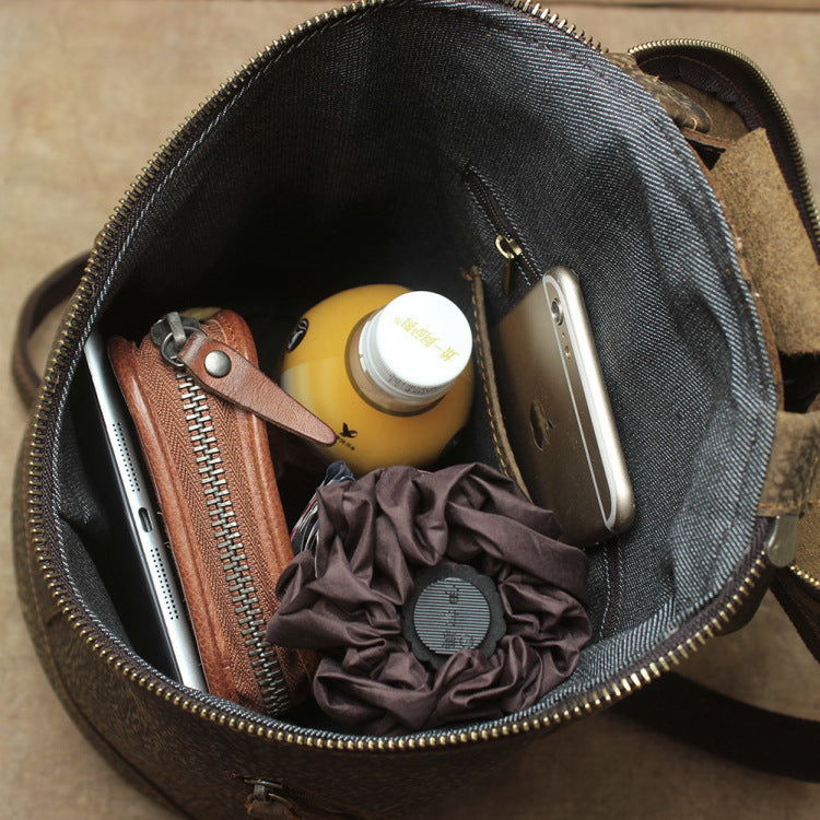 Open brown leather bag with items including a phone, bottle, and pouches.
