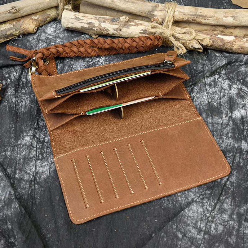 Brown leather wallet with braided strap on a textured surface