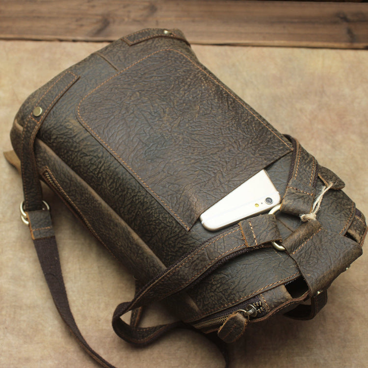Brown leather bag with a phone inside on a wooden surface