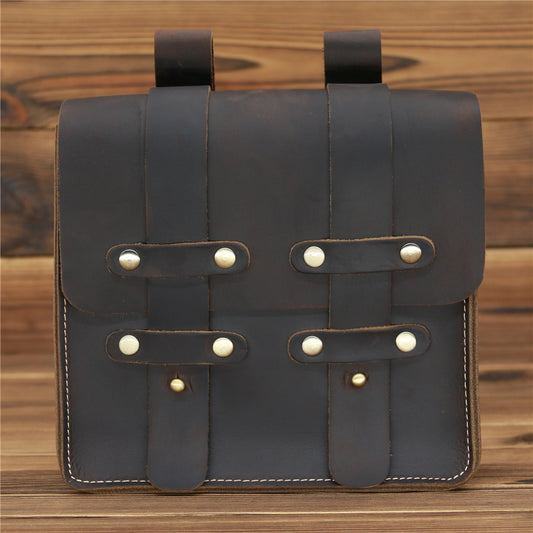 Brown leather bag with strap closures on a wooden surface