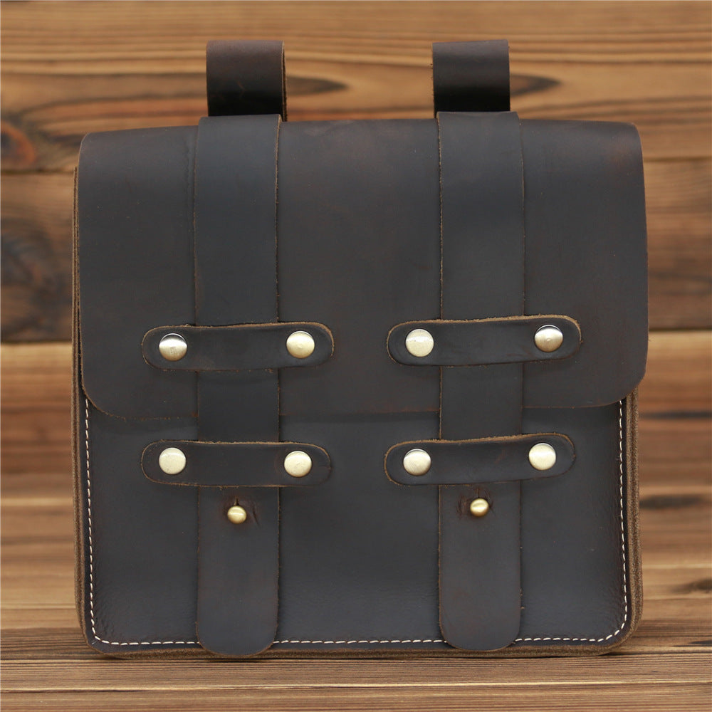 Brown leather bag with strap closures on a wooden surface