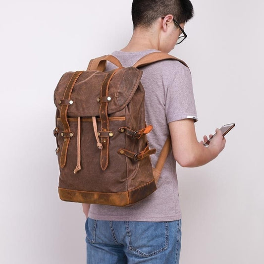 Person wearing a brown backpack holding a phone on a plain background