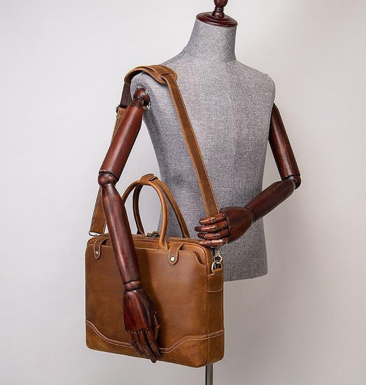Brown leather handbag held by a mannequin with a plain background
