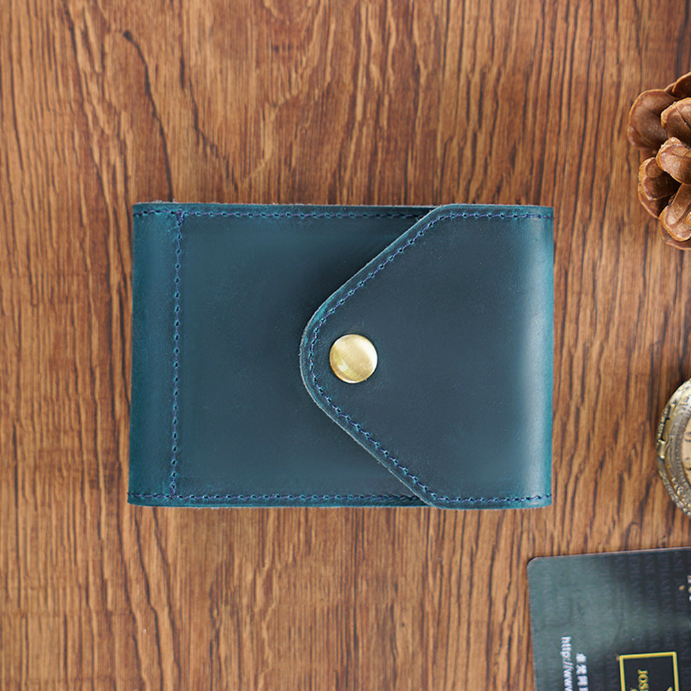 Blue leather wallet with a gold button on a wooden surface