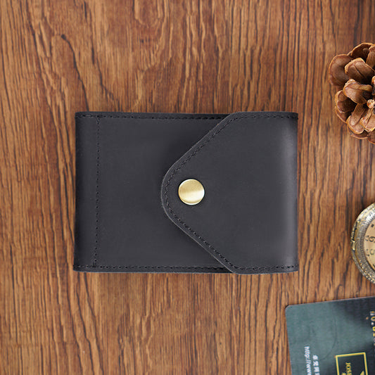 Black leather wallet with a gold button on a wooden surface