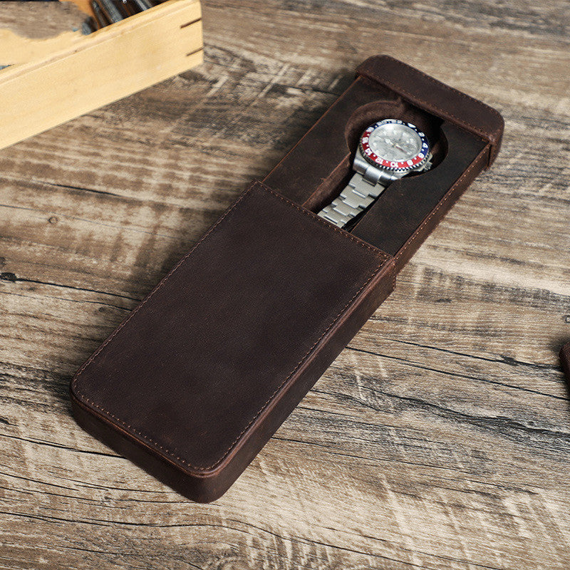 Watch in a brown leather case on a wooden surface