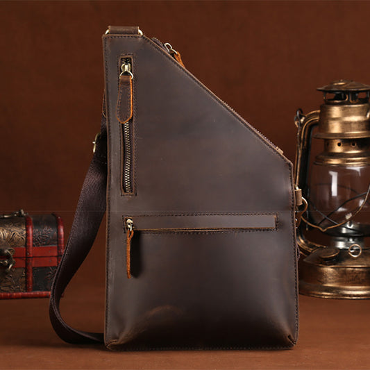 Brown leather sling bag with vintage lantern and treasure chest on a brown background