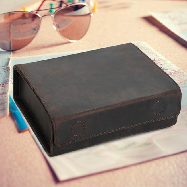 Brown leather wallet on a table with sunglasses and a map