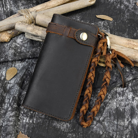 Black leather key holder with braided brown strap on a rustic background