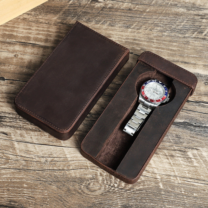 Watch with a brown leather case on a wooden surface