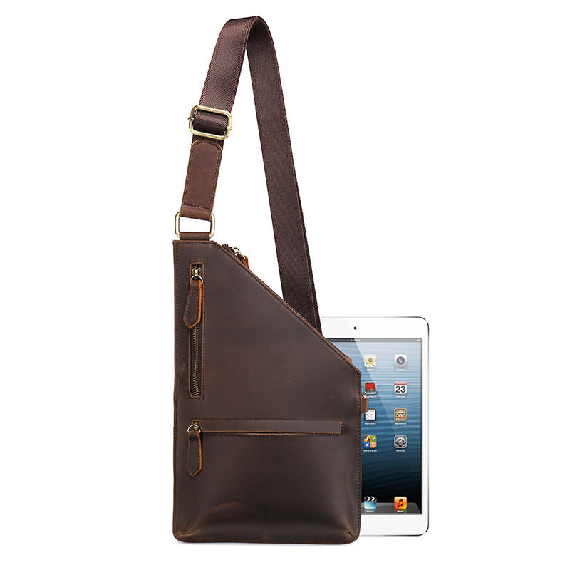Brown leather sling bag next to a tablet on a white background