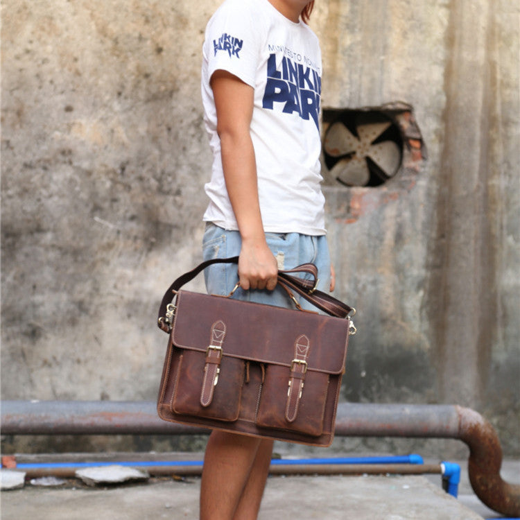 Person holding a brown leather briefcase against a textured wall background